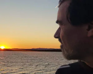 Mika blickt auf den Sonnenuntergang am Meer – ein ruhiger Abendmoment